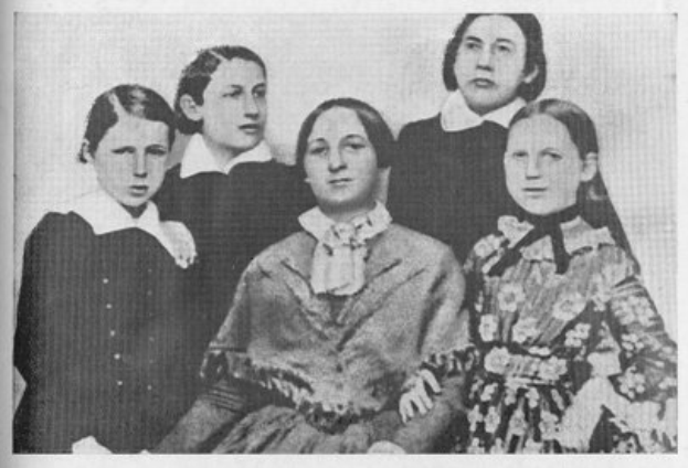 Ein Schwarz-Weiß-Foto einer Gruppe von Frauen verschiedenen Alters und Ethnien, mit einer Frau in der Mitte sitzend und Text unten, der "Die Frauenwahlrechtsbewegung" lautet.
