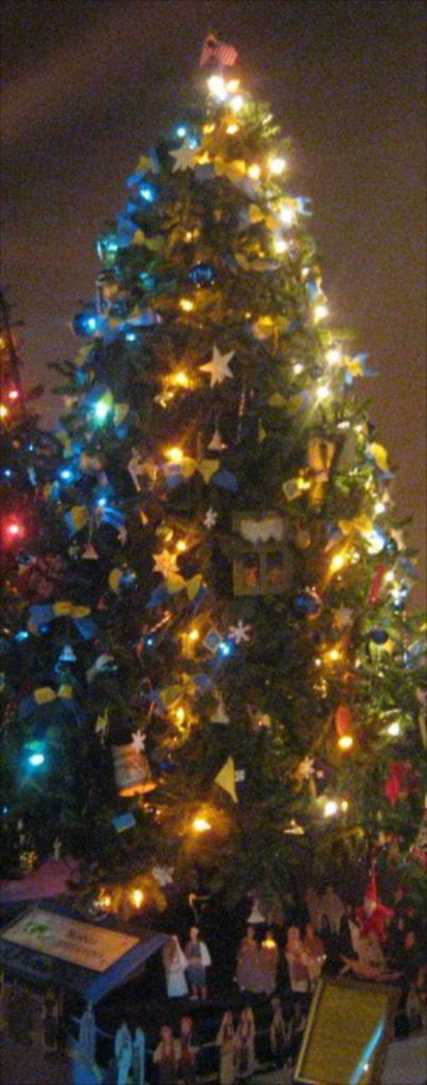 Ein geschmückter Weihnachtsbaum mit darunter platzierten Statuen auf einem Tisch.