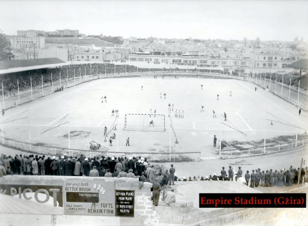 Ein Schwarz-Weiß-Foto des Empire Stadiums in Giza mit einer Gruppe von Menschen, die in der Mitte Eishockey spielen, umgeben von einem Zaun, Gebäuden und Bäumen im Hintergrund und Text unten.