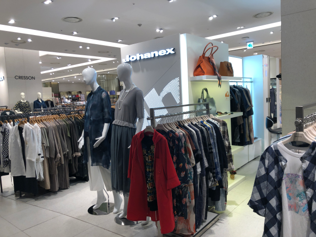 Ein Bekleidungsgeschäft mit Schaufensterpuppen, Kleiderstangen, Handtaschen, Schildern, Deckenleuchten und einer Säule, das sich im Mall of Asia als Teil der Johanex-Marke befindet.