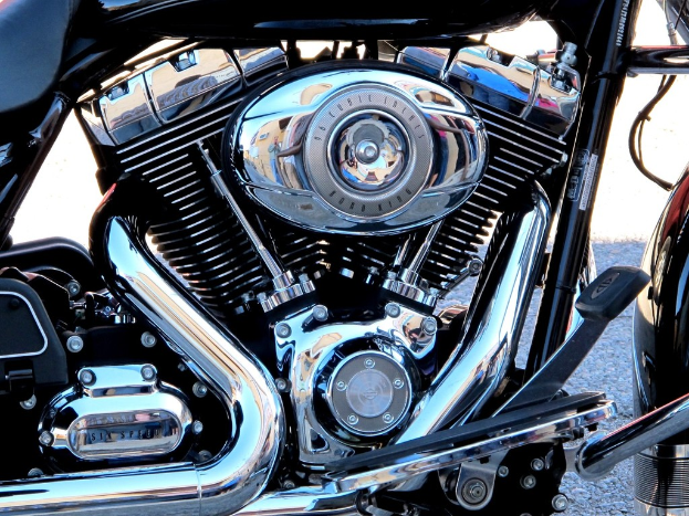 Eine Sammlung von Motorradteilen, darunter ein Motor, ein Kühler, ein Auspuffrohr, Zahnräder, Stangen, Muttern und Drähte.