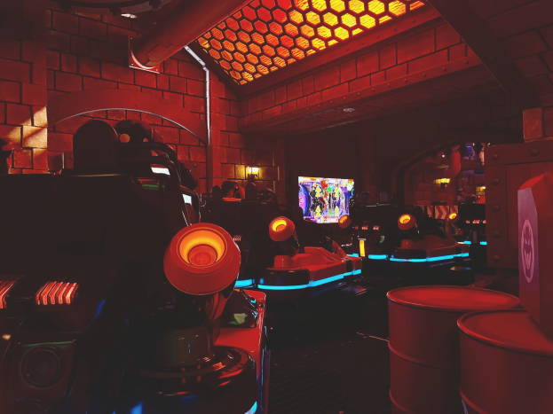 Ein hell erleuchteter Raum voller verschiedener Arcade-Videospielautomaten, Bildschirme und andere Gaming-Ausstattung, der eine lebendige Atmosphäre schafft.