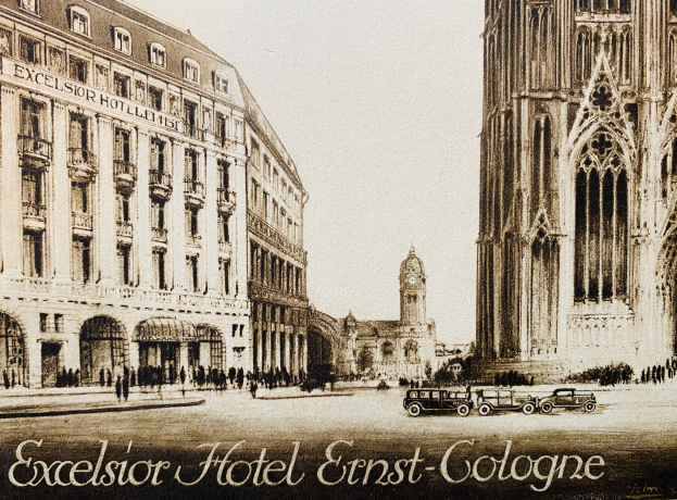 Ein Plakat des Excelsior Hotel Ernst Köln mit Fahrzeugen auf der Straße, Menschen, die gehen, und Gebäuden im Hintergrund, mit Text unten und dem Himmel oben sichtbar.