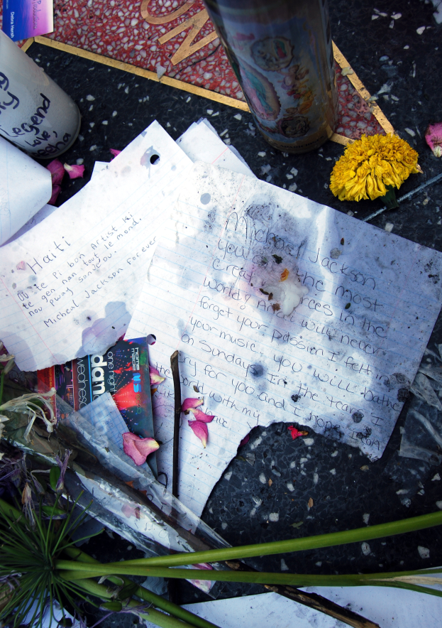 Ein Denkmal auf dem Hollywood Walk of Fame mit einem Strauß bunter Blumen, Papieren, Büchern und einem Glas auf dem Boden.