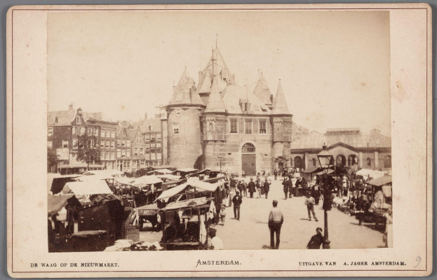Schwarz-weißes Foto eines belebten Marktes in Amsterdam mit Menschen, Ständen und Gebäuden im Hintergrund, mit Text unten.