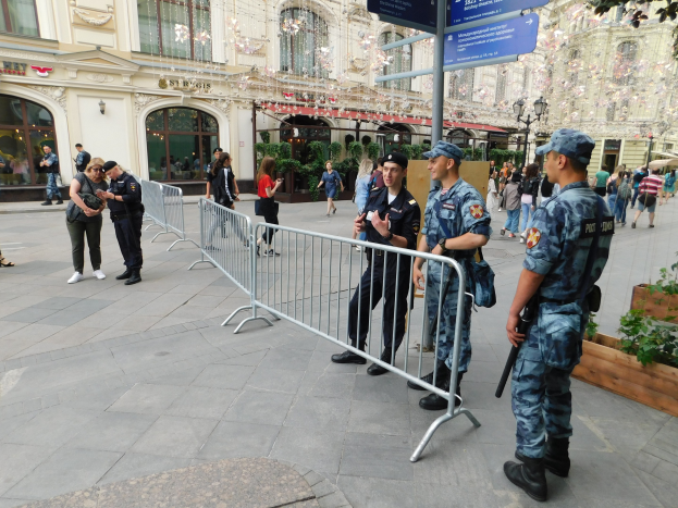 Polizisten in Uniform stehen vor einer Menge, einige mit Waffen, mit Absperrungen und Schildern im Vordergrund und Gebäuden, Bäumen und Laternen im Hintergrund während einer Anti-Terror-Operation in Wien, Österreich.