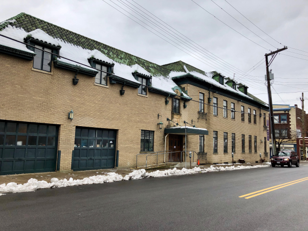 Ein großes Ziegelgebäude mit einem grünen Dach an einer Straßenecke, umgeben von Fahrzeugen, Schnee, Strommasten, Bäumen und einem bewölkten Himmel, identifiziert als das ehemalige St. Louis Fire Station.