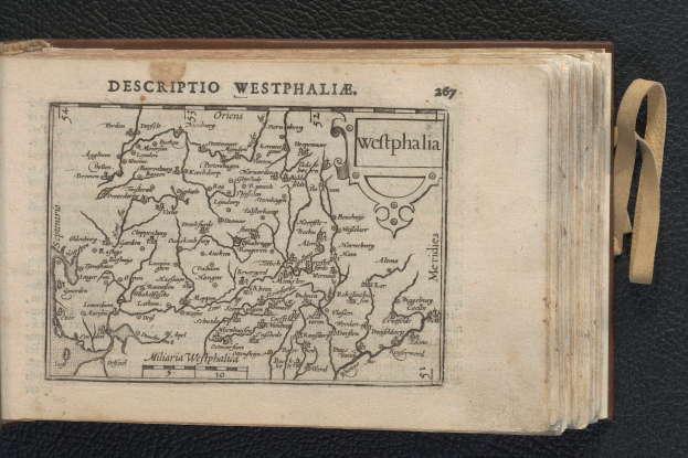 Ein aufgeschlagenes Buch mit einer detaillierten Karte der geografischen Merkmale Westphalens, das auf einer schwarzen Oberfläche liegt.