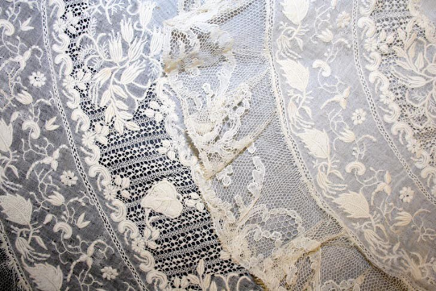 Nahaufnahme eines weißen Hochzeitskleids mit feiner Spitzenverzierung, das zarte Muster und leichten, luftigen Stoff zeigt.