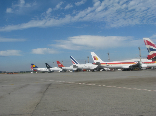 Eine Start- und Landebahn mit wenigen Flugzeugen, Polen, Kabeln und einigen Wolken am Himmel.