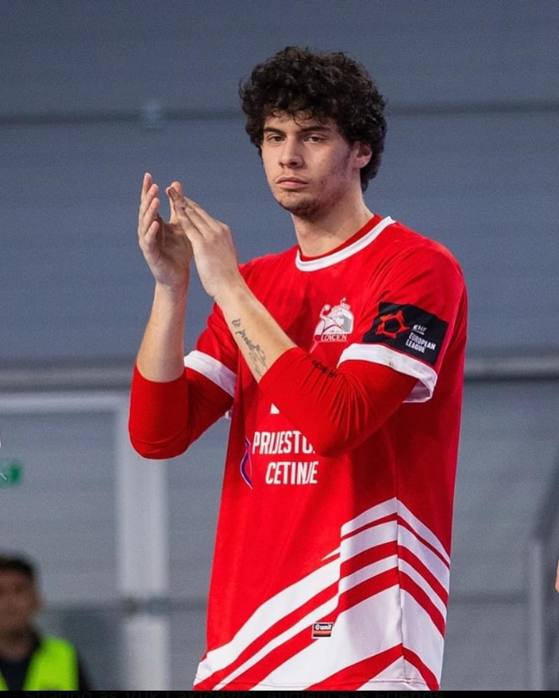 Ein Mann in rot-weißem Shirt klatscht in der Vordergrund mit einer anderen Person und einer Wand im Hintergrund, Text unten lautet "Copenhagen Futsal Club - Foto 1".