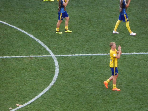 Gruppe von Männern in Fußballtrikots klatscht auf einem Fußballfeld.