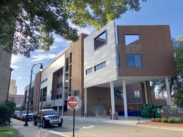 Großes Gebäude mit der Aufschrift "Stadthallen Apartments" mit vielen Fenstern, umgeben von Straßeninfrastruktur, Fahrzeugen, Grünflächen und einem bewölkten Himmel.