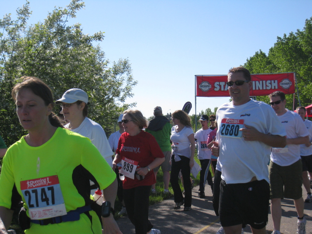 Eine Gruppe von Kindern, die bei einem Marathonlauf teilnehmen, mit einem roten Banner und Bäumen im Hintergrund.