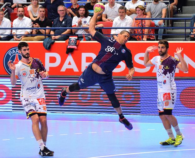Männer spielen Handball auf einem Court mit einem Ball in der Mitte, Zuschauer im Hintergrund und einem Banner mit der Aufschrift "Futsal World Cup 2015 - Paris Saint-Germain vs Olympique Lyon".