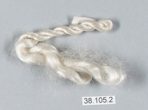 Eine Faser weißer Seidenfaden mit einer Zahl darauf, der auf einer grauen Oberfläche liegt.