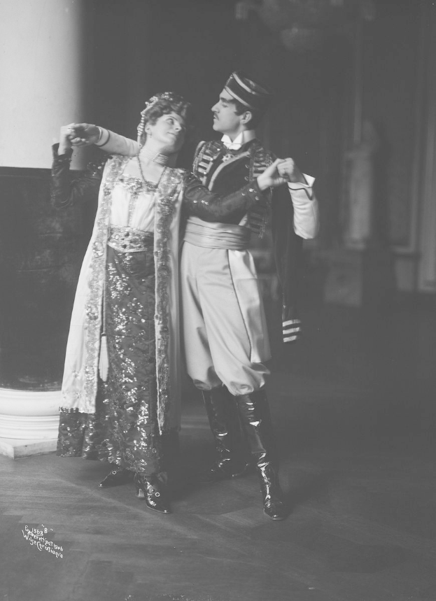 Schwarzes und weißes Foto eines Mannes und einer Frau, die in einem Ballsaal tanzen, mit einer Säule und einer Wand im Hintergrund; der Mann trägt Tanzschuhe.