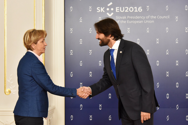 Bundeskanzlerin Angela Merkel und Bundespräsident Joachim Gauck schütteln sich die Hände vor einer Wand mit einem "EU-Gipfel"-Plakat und einer Tür im Hintergrund, beide lächeln.