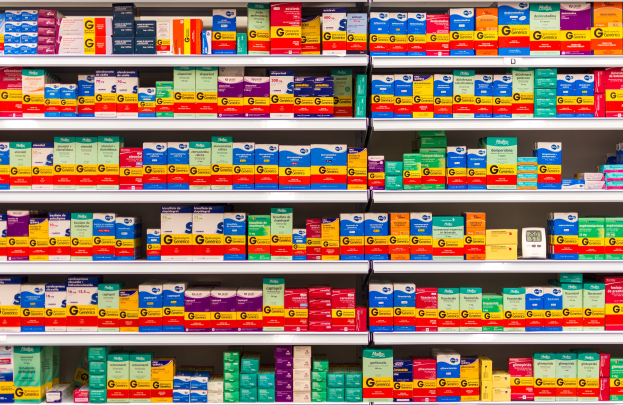 Ein Apothekenregal voller verschiedener Medikamente, Schachteln und anderer Gegenstände, die ordentlich auf den Regalen angeordnet sind.
