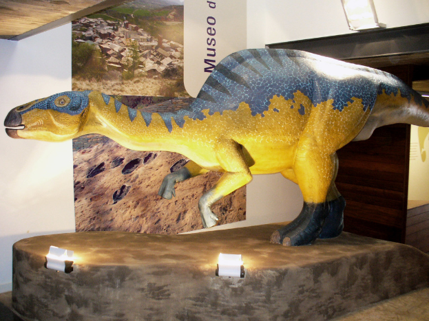 Ein Dinosaurier-Idol mit zwei Lichtern davor und einem Banner an der Wand dahinter.