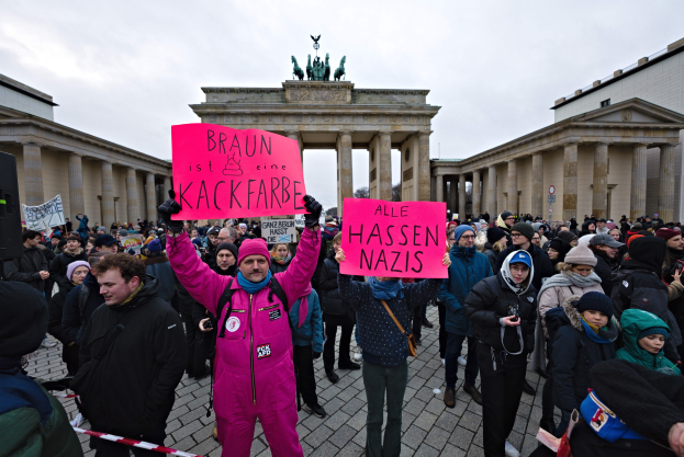 Gruppe von Menschen protestiert vor dem Brandenburger Tor in Berlin, hält Schilder gegen die Anti-Nazi-Bewegung der deutschen Regierung.