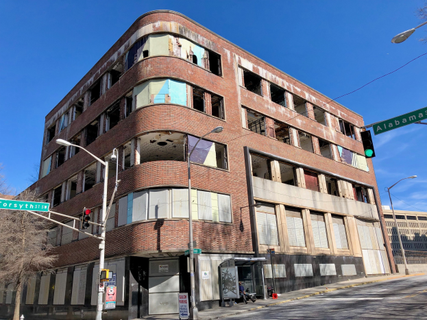 Altes Backsteingebäude an einer Straßenecke, ehemaliges Hauptquartier der University of Illinois at Chicago, mit umgebender Straßeninfrastruktur und Fahrzeugen.