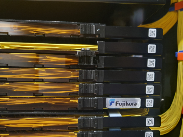 Ein Nahaufnahme-Bild eines Server-Racks in einem Rechenzentrum, mit verschiedenen elektronischen Geräten und Verbindungsdrähten, die ein Netzwerk bilden.