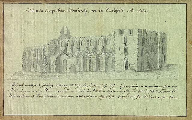 Ein detaillierter Scherenschnitt einer verfallenen Kirche in Deutschland mit detaillierten architektonischen Elementen wie Fenstern, Bögen und Säulen, vor einer grünen Landschaft, begleitet von beschreibendem Text auf dem Papier.