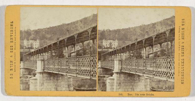 Altes Schwarz-Weiß-Foto einer Brücke, die einen Fluss in Leipzig, Deutschland, überspannt, mit Gebäuden, Bäumen und einem Hügel im Hintergrund.