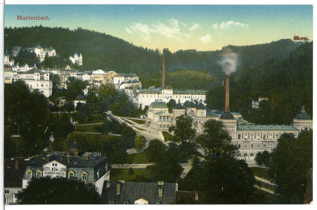 Altes Schwarz-Weiß-Foto einer Stadtlandschaft mit Gebäuden, Bäumen, Straßen, Gras, Strommasten, Rauch, fernen Hügeln und einem bewölkten Himmel, mit Text oben.