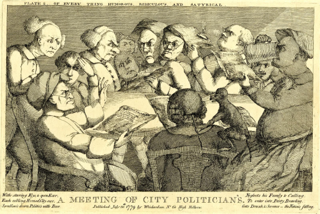 Eine Gruppe von Menschen sitzt um einen Tisch, wobei eine Person ein Buch hält, während andere in ein Gespräch vertieft sind.